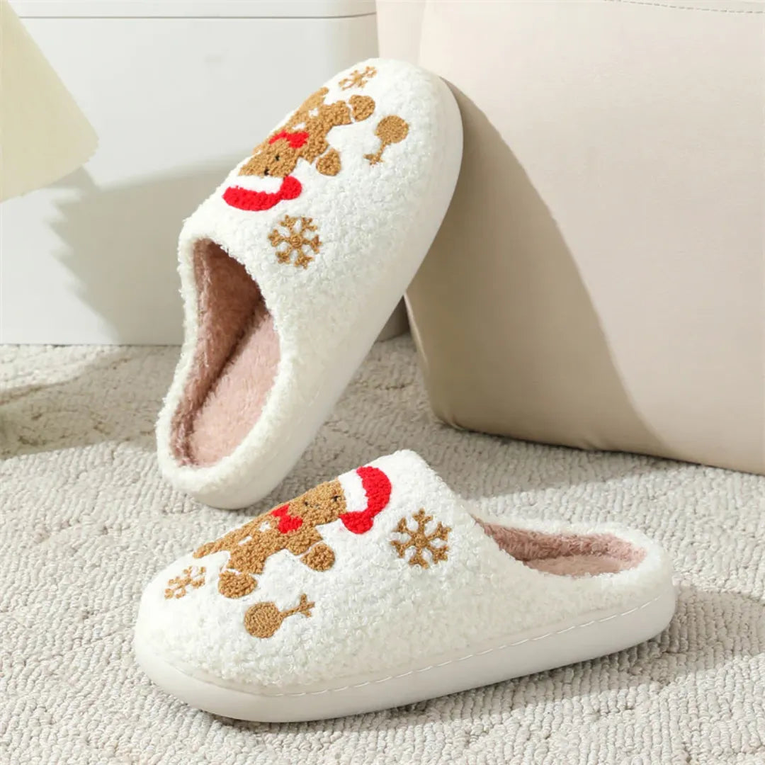 Pair of christmas cute white slippers with gingerbread design on a carpeted floor.