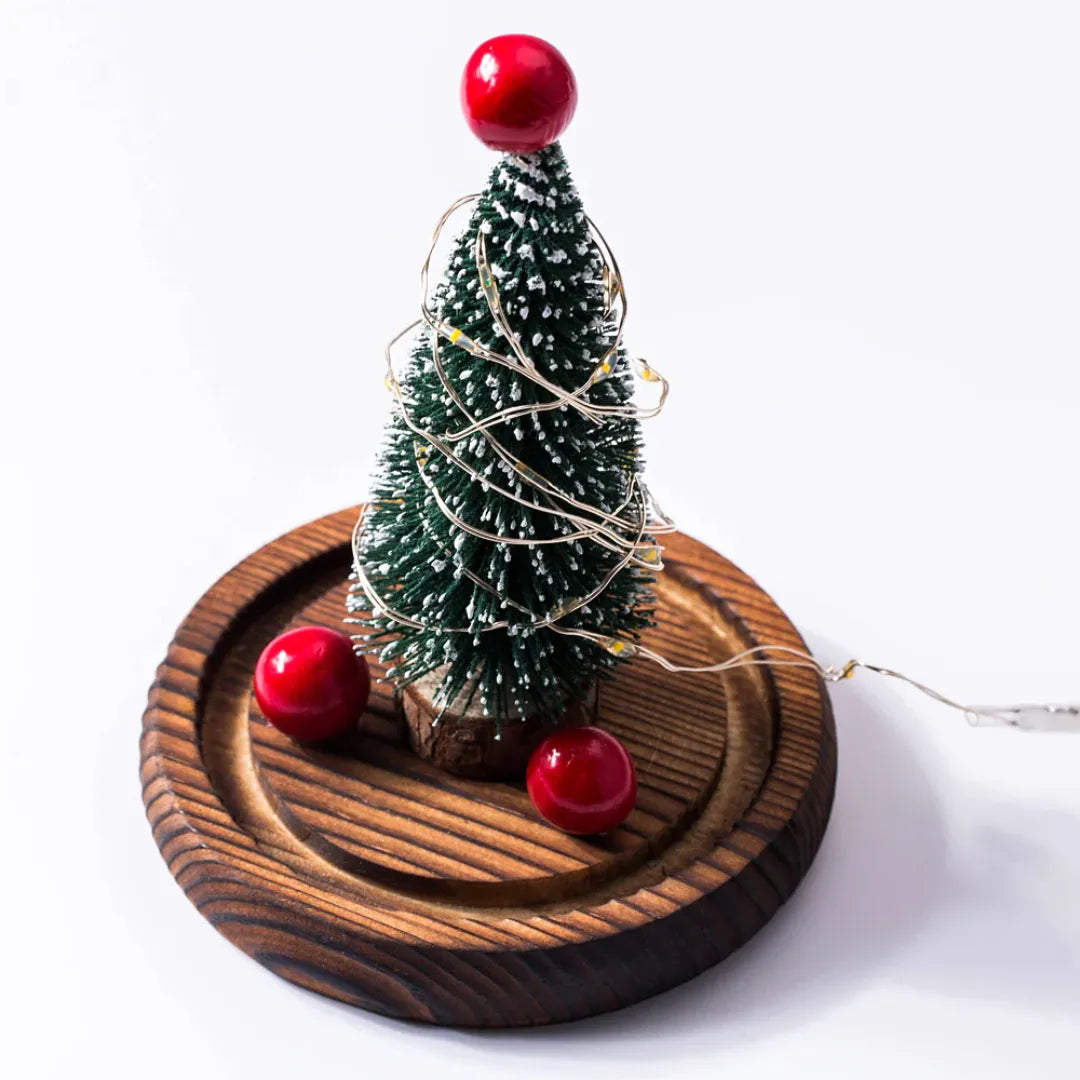 Small Christmas tree with red berries on a wooden base with fairy lights