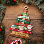 Wooden Christmas tree ornament with custom family names and year on a wooden background with festive decorations.
